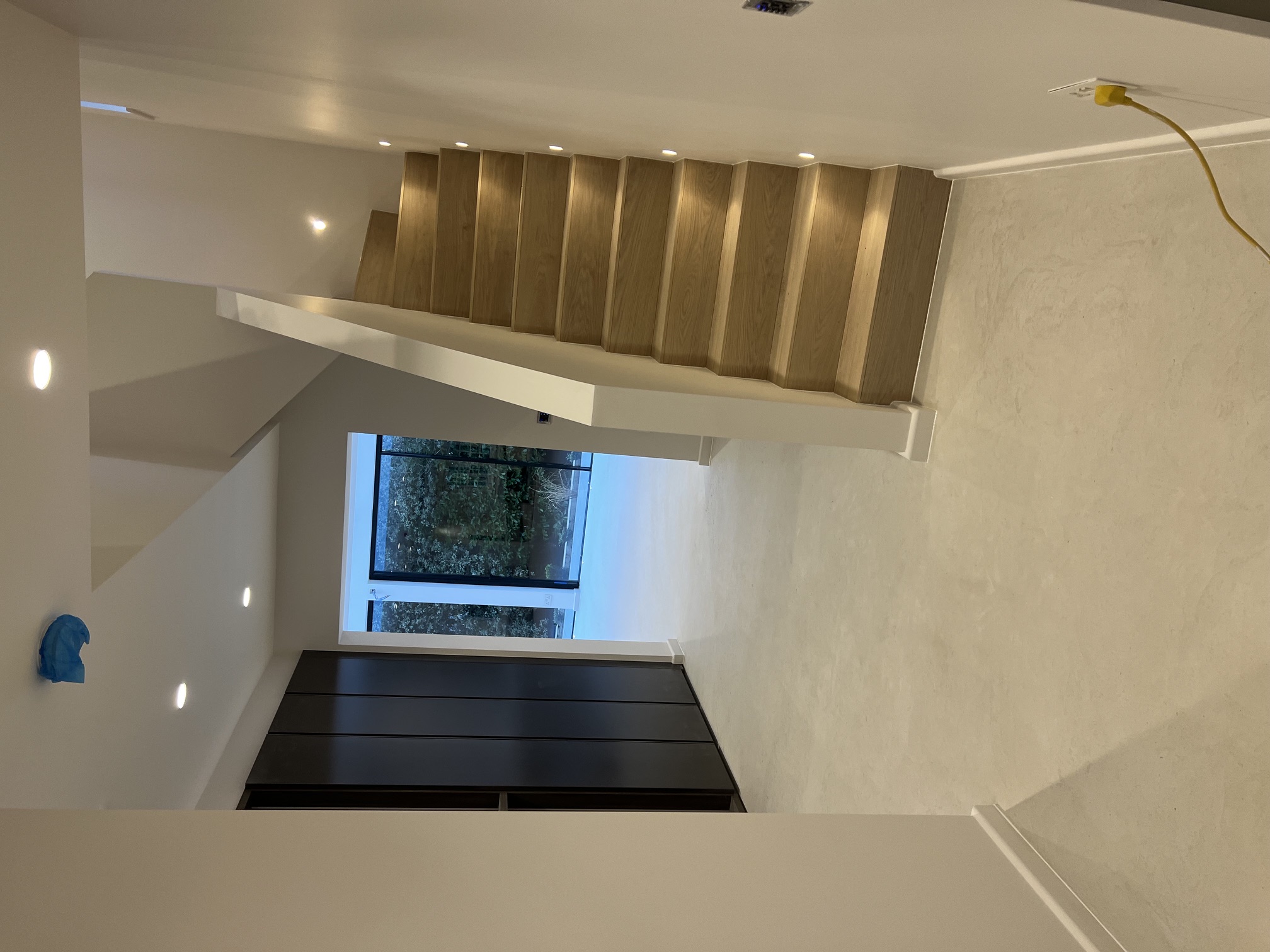Finished hallway with oak staircase and microcement floor by MM Contractors London